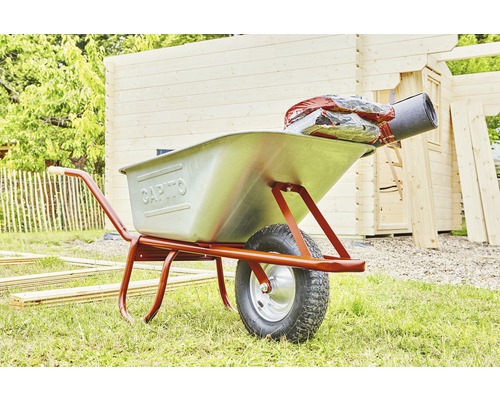 Brouette avec matériaux de construction devant une maison en bois