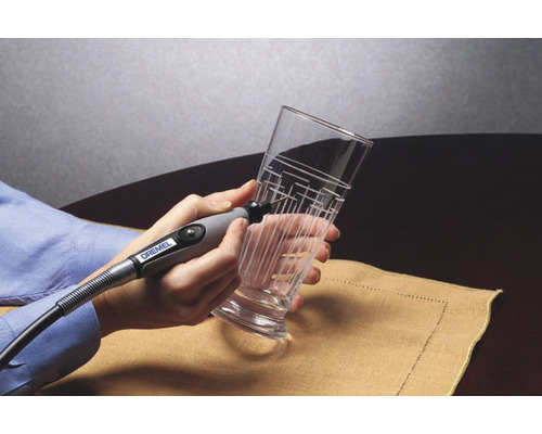 Une personne grave un verre avec un appareil à graver et un motif de lignes.