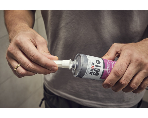 Anwender befestigt die Spitze einer Kartusche Sanitärsilikon