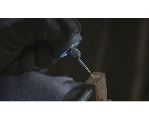 Gros plan d''une main gantée gravant une forme dans un objet métallique à l''aide d''un burin graveur