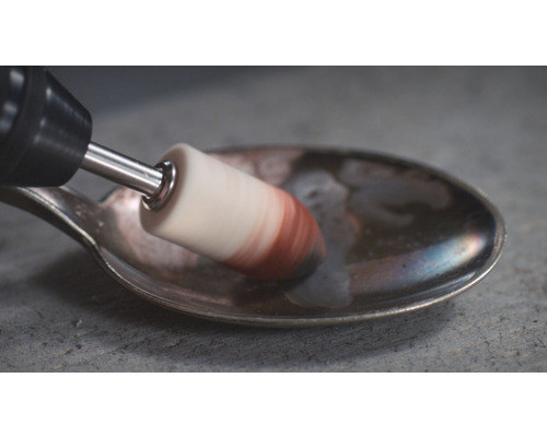 Une brosse rotative polit une cuillère.