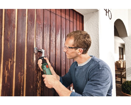 Un homme travaille sur une porte en bois avec une ponceuse multifonction.
