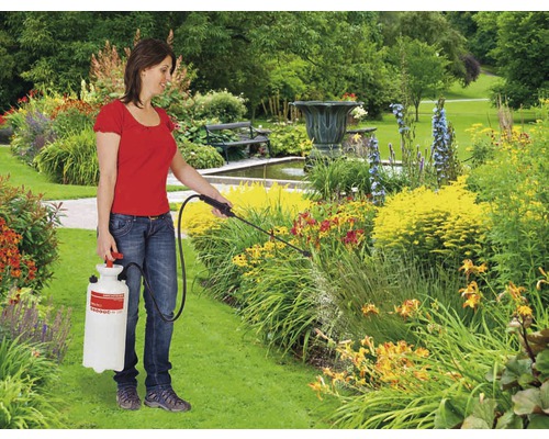 Une femme utilise un pulvérisateur de jardin pour l''entretien des plantes dans le jardin.