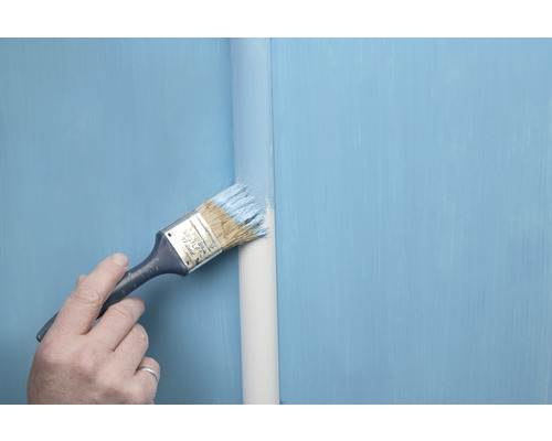 Eine Person streicht ein Rohr mit einem Pinsel und Farbe.