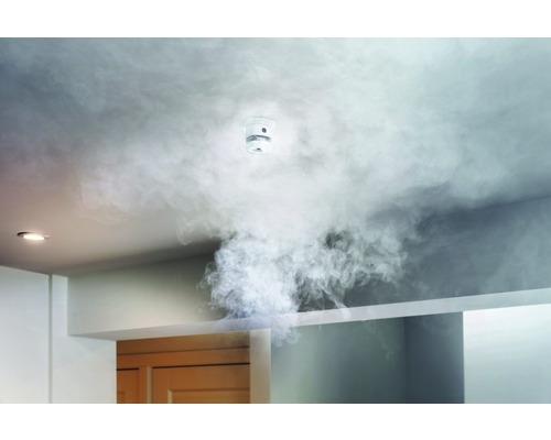 Détecteur de fumée au plafond avec de la fumée dans une pièce