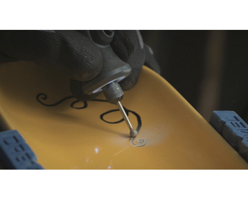 Une personne grave un motif dans une pièce à l''aide d''un outil multifonction.