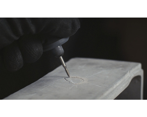 Une personne grave un objet avec une machine à graver.