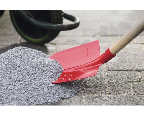 Pelle rouge avec manche en bois dans un tas de gravier