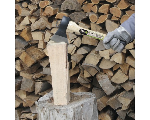 Axt spaltet Holzscheit vor Holzstapel