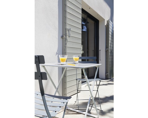 Gartenszene mit Klapptisch und Klappstühlen vor geschlossenem Fensterladen