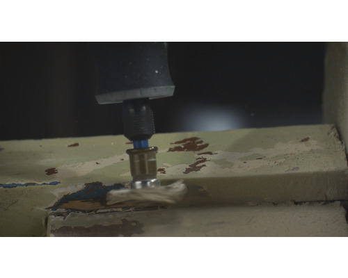 Une perceuse ponce la peinture d''un cadre de fenêtre.