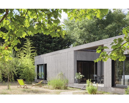 Modernes Holzhaus mit Gartenmöbeln und Grünpflanzen