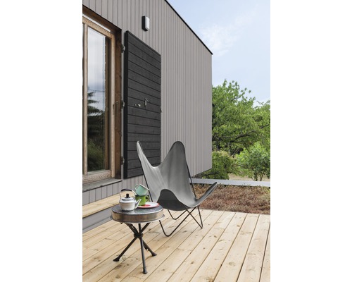 Terrasse avec platelage en bois, chaise papillon et table d''appoint devant une maison avec fenêtre et volet