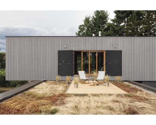 Maison moderne avec façade en bois, toit végétalisé et terrasse avec chaises longues