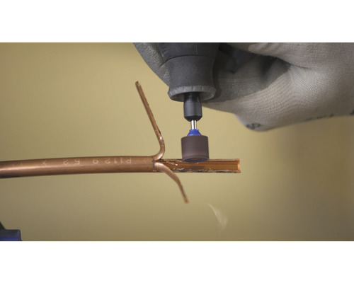 Une personne utilise un outil multifonction pour couper un tuyau.