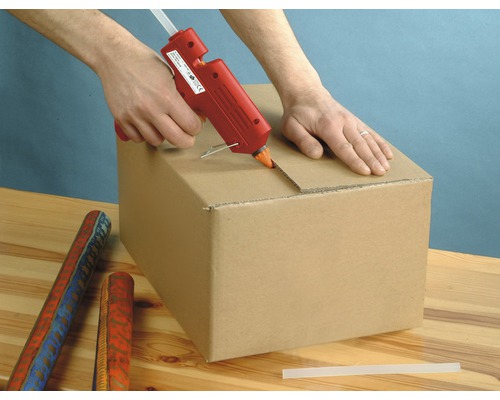 Une personne utilise un pistolet à colle chaude pour fermer un carton.