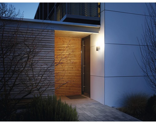 Aussenansicht eines modernen Hauses mit Holzfassade, Steinweg und beleuchteter Eingangstür