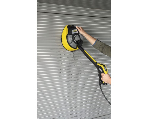 Une personne nettoie un volet roulant avec une brosse rotative de Kärcher.