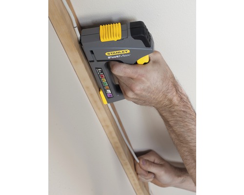 Eine Person befestigt mit einem Stanley FatMax Kabeltacker ein Kabel an einem Holzrahmen.
