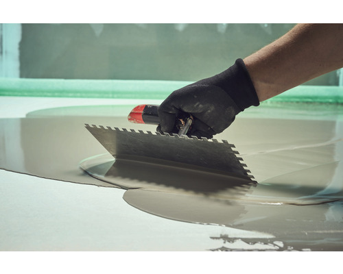 Artisan étalant un ragréage avec une spatule