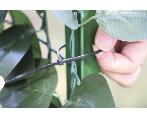 Gros plan sur la fixation d''une haie artificielle avec un collier de serrage.