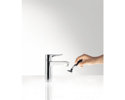 Einhebelmischer im Badezimmer mit Hand, die einen Rasierer reinigt