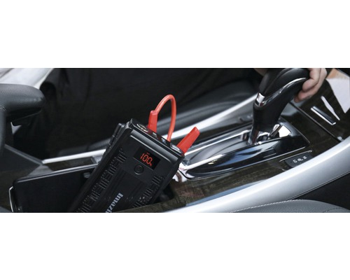 Tragbarer Auto-Starthilfe-Booster im Auto mit 100 Prozent Akkuladung auf dem Display.