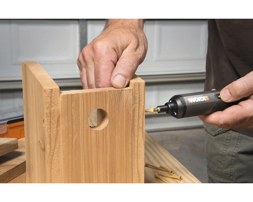 Une personne utilise un tournevis pour assembler un nichoir en bois.