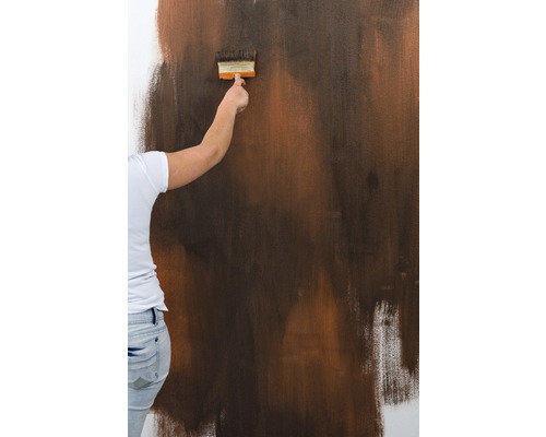 Eine Person streicht eine Wand mit einem Pinsel.