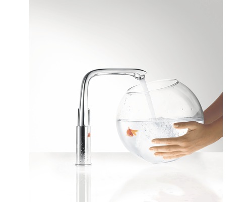 Un robinet remplit un bocal en verre avec de l''eau, dans lequel nage un poisson rouge.