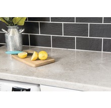 Plan de travail de cuisine avec planche à découper, citron et couteau devant un dosseret carrelé