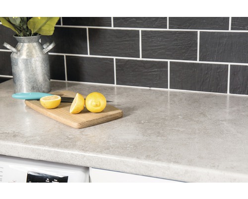 Plan de travail de cuisine avec planche à découper, citron et couteau devant un dosseret carrelé