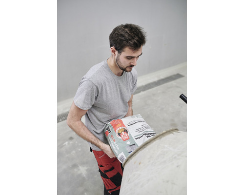 Ein Mann schüttet Betonmischung in einen Betonmischer.