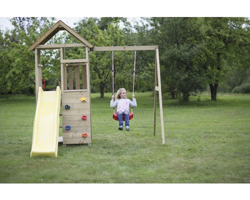 Enfant sur une balançoire sur une tour de jeux avec toboggan et mur d''escalade dans le jardin