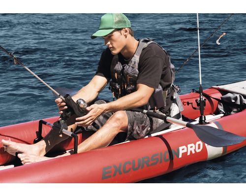 Un homme pêche dans un kayak gonflable rouge sur l''eau.