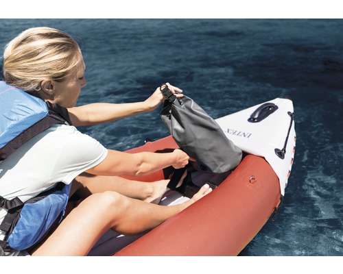 Une femme range un sac étanche dans un kayak gonflable de la marque Intex
