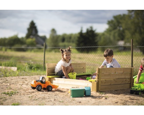 Des enfants jouent dans un bac à sable avec des jouets à l''extérieur