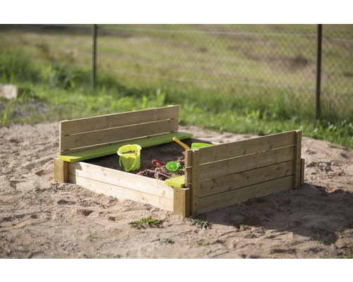 Bac à sable en bois avec des jouets dans le jardin