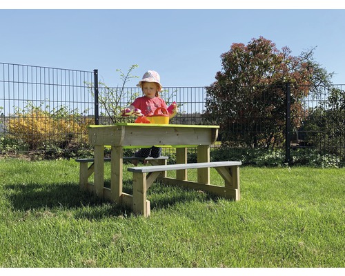 Enfant assis sur un groupe de sièges en bois avec bac à sable dans le jardin