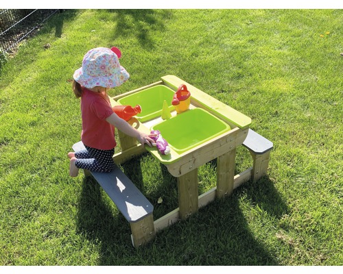 Enfant jouant à une table de sable et d''eau avec des bancs dans le jardin.