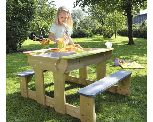 Enfant jouant à une table à sable et à eau avec des bancs de jardin.