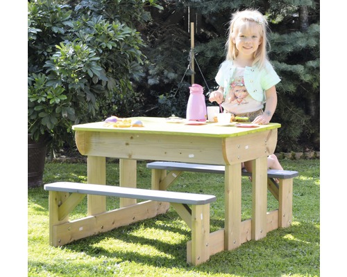Enfant assis à une table de pique-nique avec des bancs dans le jardin.