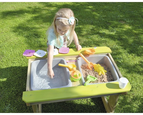 Fille jouant à la cuisine de boue avec du sable et de l''eau dans le jardin