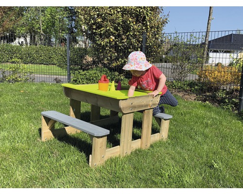 Enfant jouant à une table à sable avec banc en bois dans le jardin