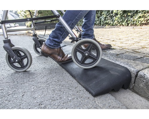 Personne avec un déambulateur utilisant une rampe de trottoir pour la transition
