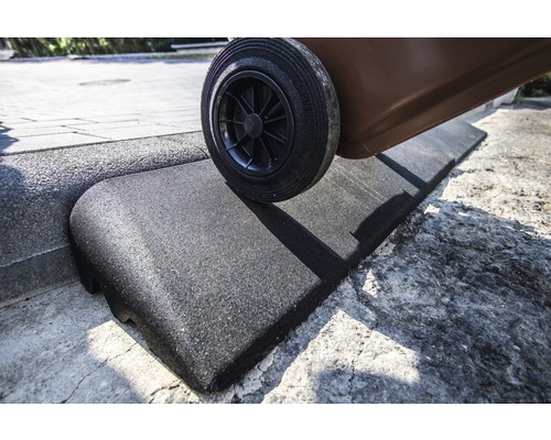 Une poubelle roule sur une rampe de trottoir en caoutchouc.