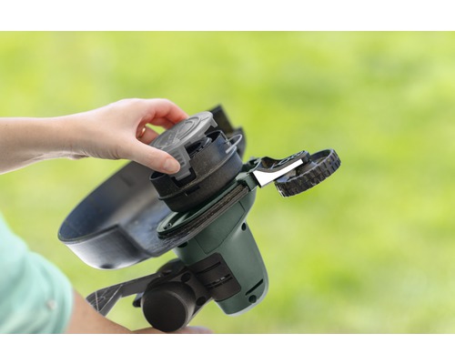 Une personne remplace la bobine d''un coupe-bordure.