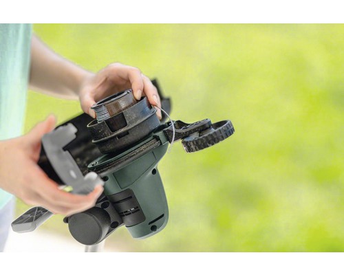 Les mains changent la bobine d''un coupe-bordure