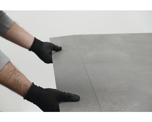 Personne portant des gants posant un revêtement de sol