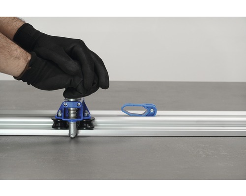 Coupe-carrelage en cours d''utilisation avec des gants sur un rail de guidage en aluminium